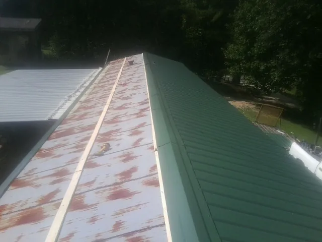 Old rusted panels beside newly installed green metal roofing — Wind Damage Roof Repair by Roofing Brothers in Teasdale