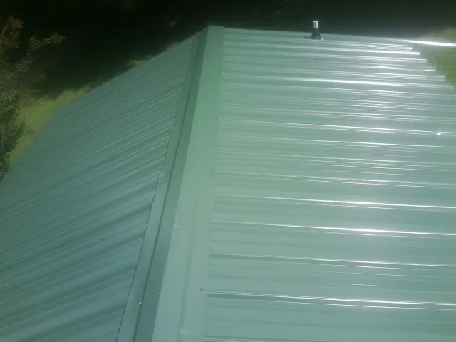 New green metal panels meeting at the ridge of a roof — Flat Roof Repair work by our crew in Teasdale