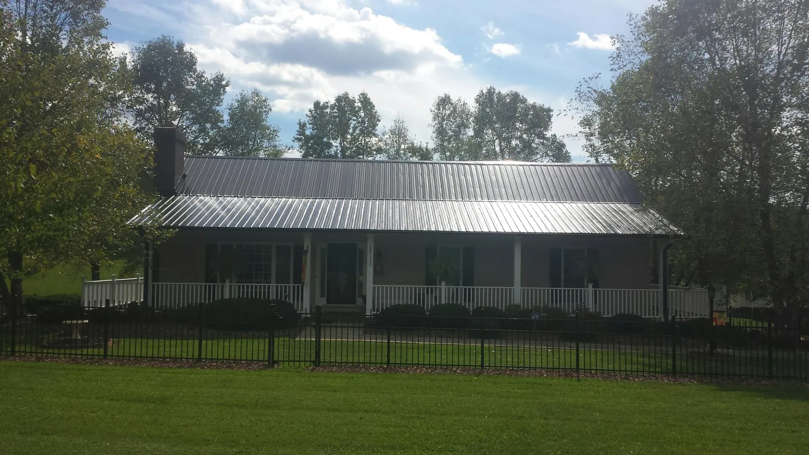 Gray metal roof on a brick ranch with a full width front porch — Gutter Guard Installation work by our crew in Teasdale