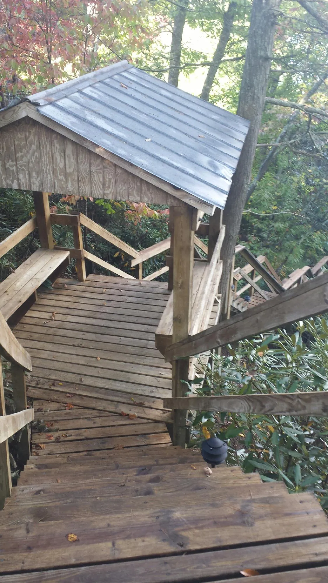 Metal roofed shelter over wooden steps on a wooded walkway — Skylight Repair & Installation work by our crew in Teasdale
