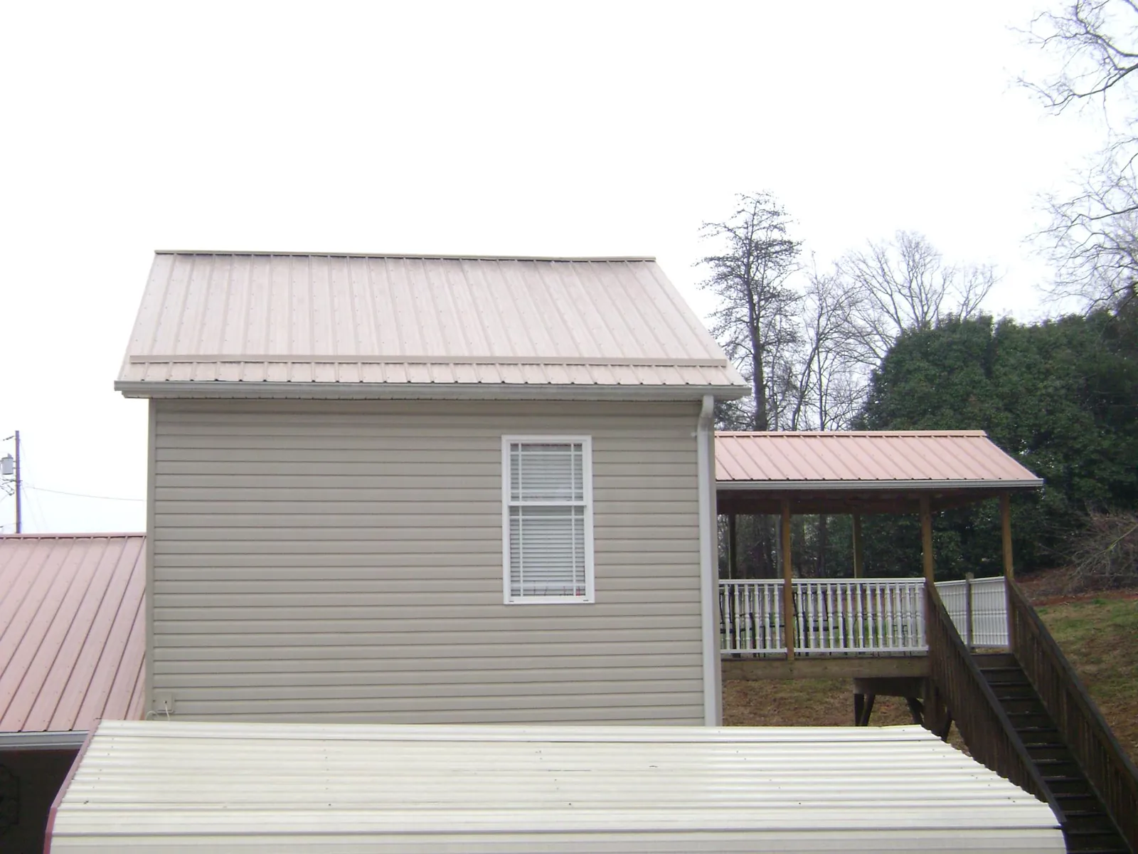 Tan metal roofs on a two story addition and attached porch, from a Roof Replacement job in Teasdale