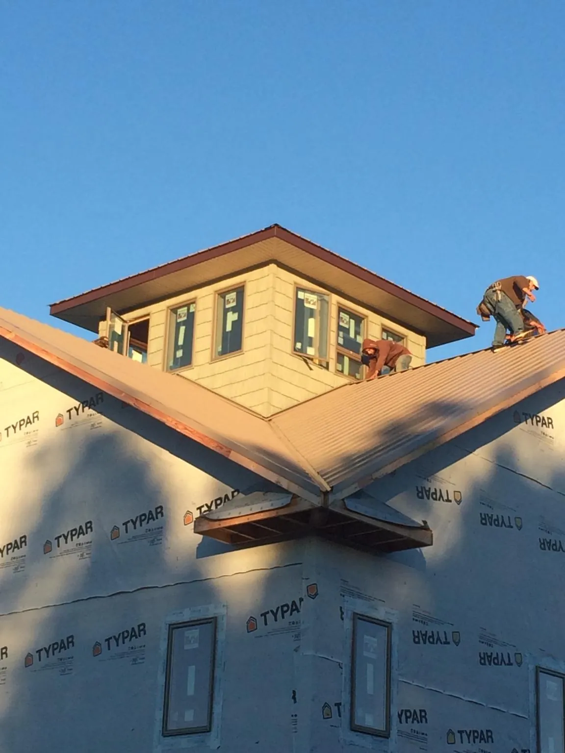 Roofers working around a rooftop cupola on a new metal roof at sunset — Roof Waterproofing in Teasdale by Roofing Brothers